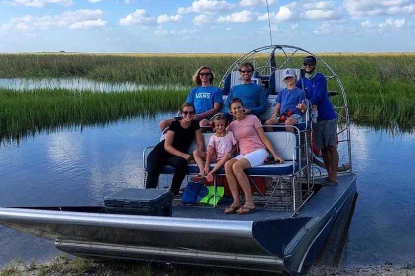 A group of people on a boat in a marshy area. 3