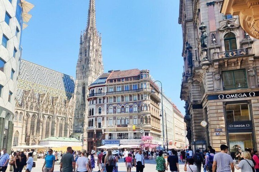 A busy urban square with historic buildings, a prominent cathedral spire, and a modern glass structure. 4
