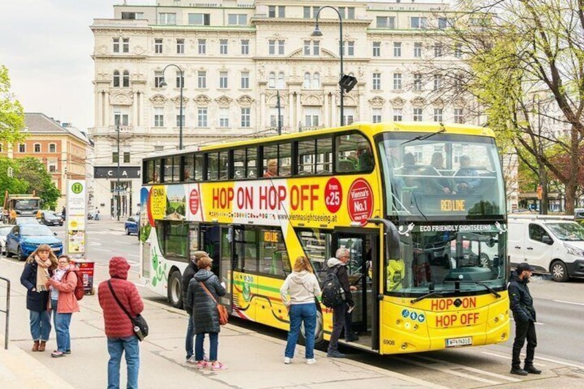 A yellow double-decker bus with 'HOP ON HOP OFF' advertising on its side. 2