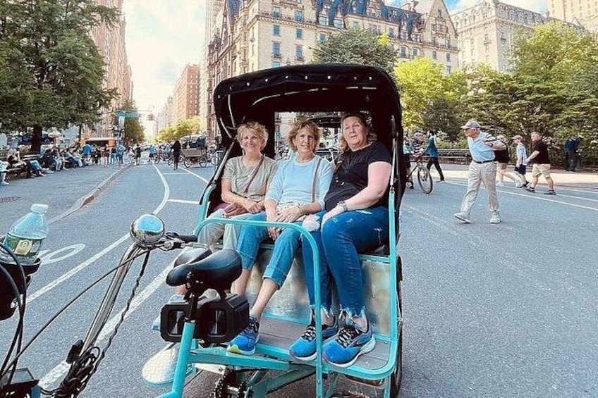 A vintage rickshaw with two passengers on a city street. 4
