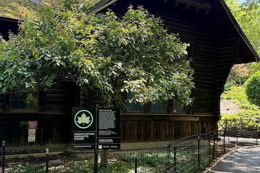 A wooden cabin with a signboard, surrounded by a fenced area and greenery. 5