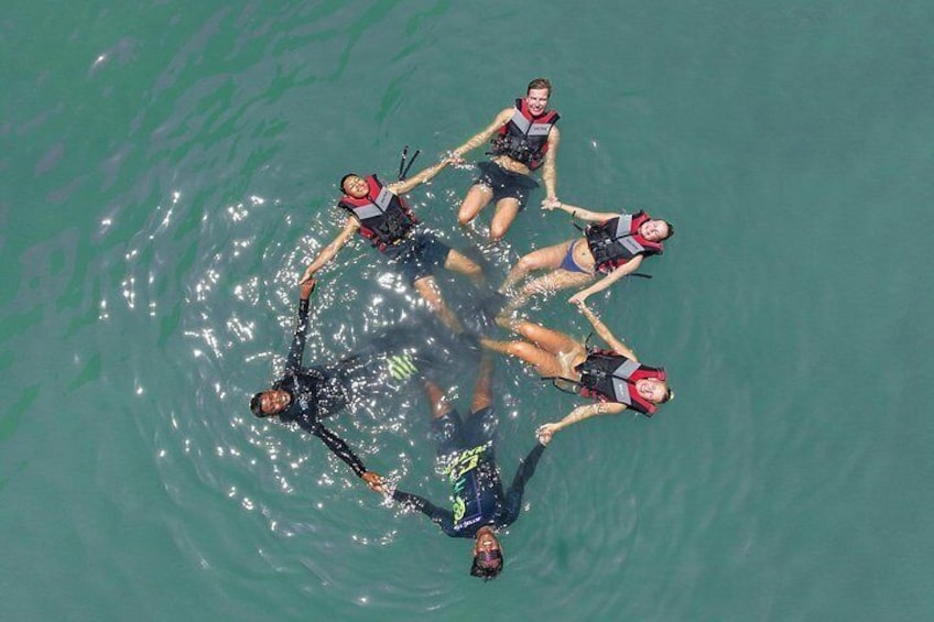 Un groupe de personnes pratiquant la plongée sous-marine en formation circulaire dans une eau claire. 2