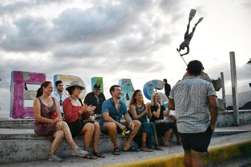A group of people sitting on steps with large colorful letters spelling 'EDEN' behind them. 4