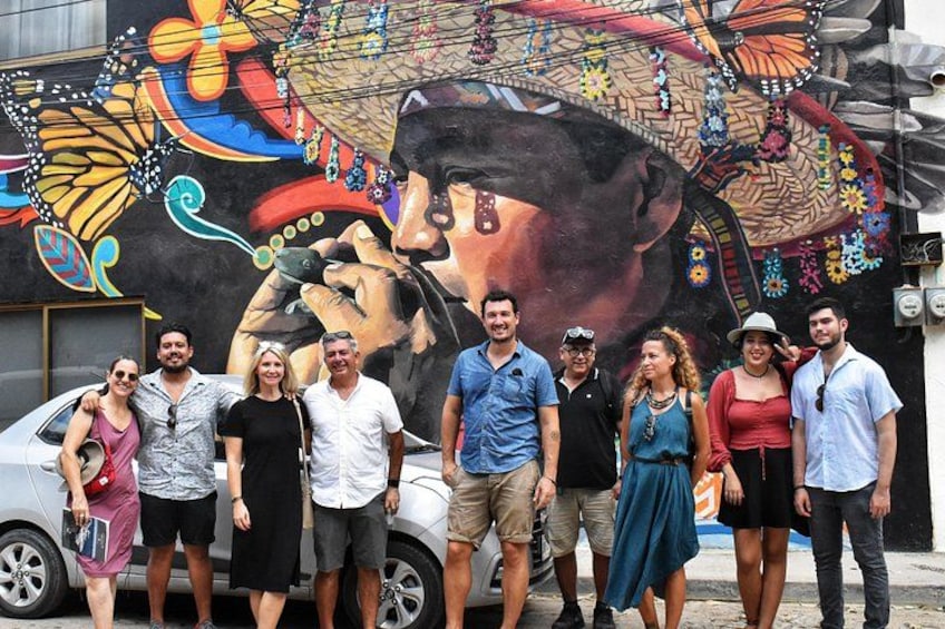A group of people standing in front of a mural with a large butterfly and floral patterns. 5