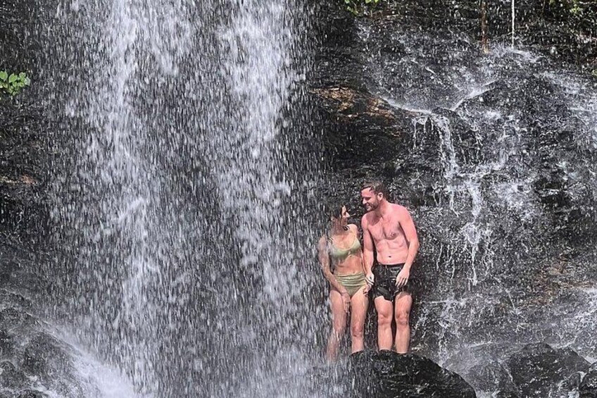 A waterfall with a couple standing on a rock. 2