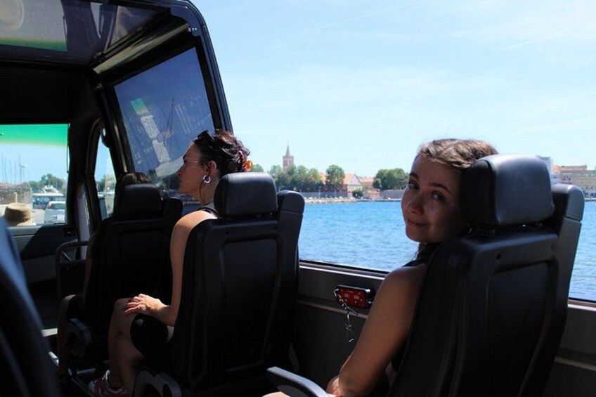 Two passengers on a boat with a view of a body of water and buildings in the background. 5