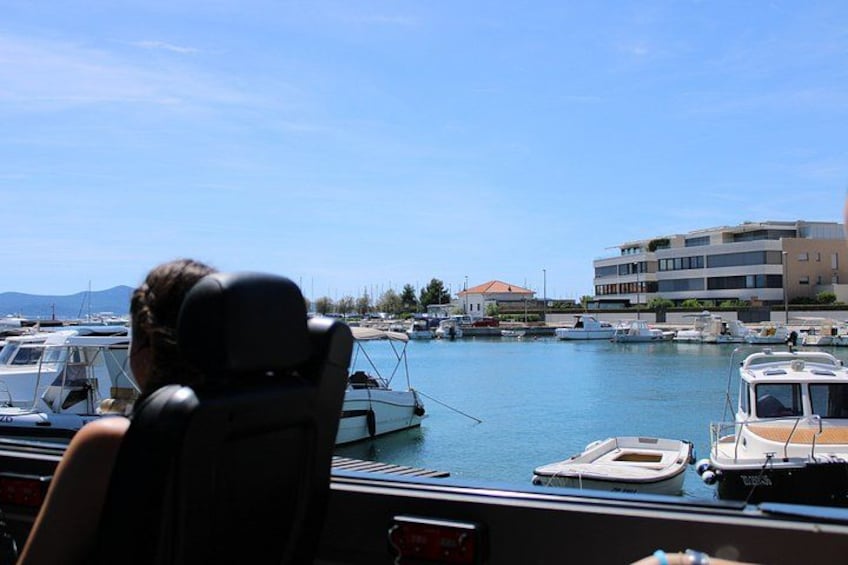 A marina with boats, a person in a boat, and buildings in the background. 2