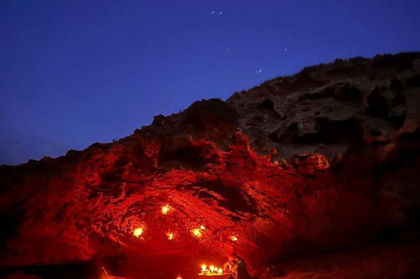 A night scene with red rock formations illuminated by artificial lights. 3
