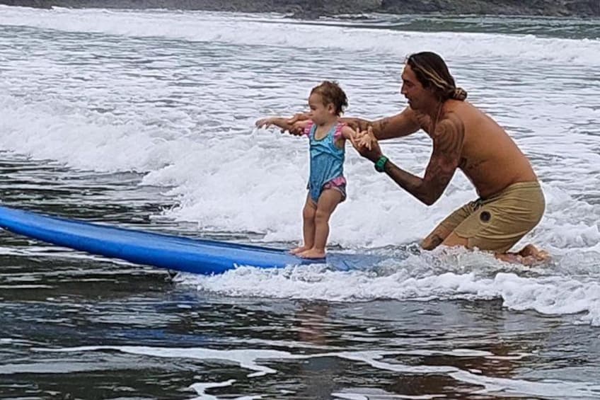En person och ett barn på en surfbräda i havet. 2