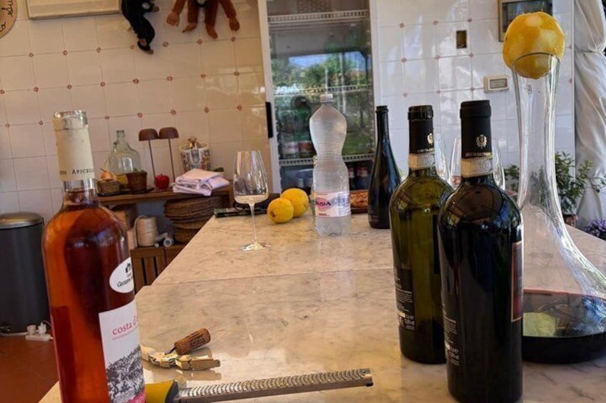 Un comptoir de cuisine avec des bouteilles de vin, un verre à vin, des citrons et un tire-bouchon. 3