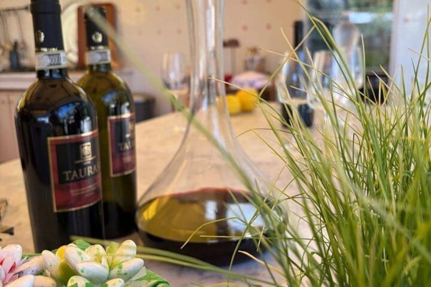 Deux bouteilles de vin, un verre de vin rouge et une plante sur le comptoir de la cuisine. 4
