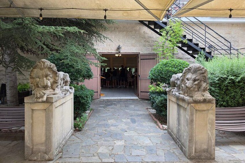 Un chemin de pierre menant à l’entrée d’un bâtiment, bordé de statues de lions, et surmonté d’un auvent. 3