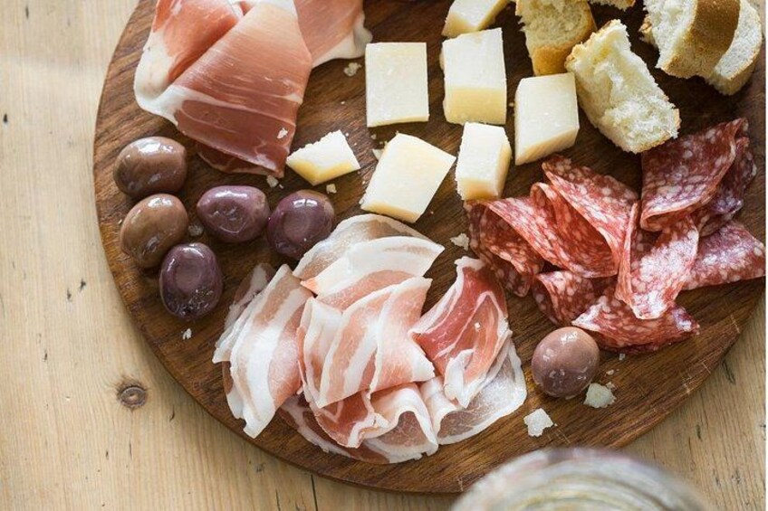 Una tabla de madera con diversos embutidos, queso y aceitunas. 2