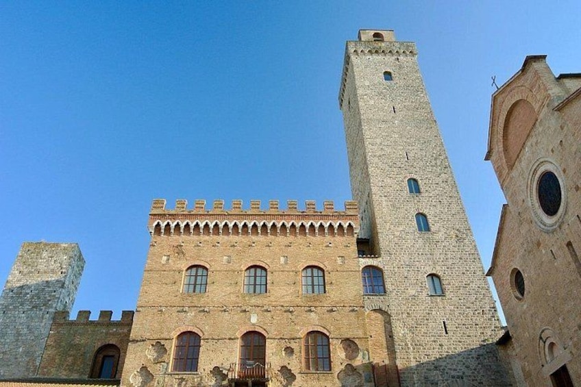 Un edificio histórico con una torre destacada y ventanas de arco. 2