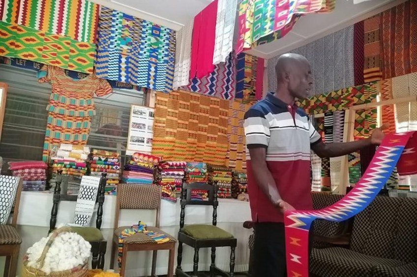 A shop with colorful fabrics and a man holding a fabric. 1
