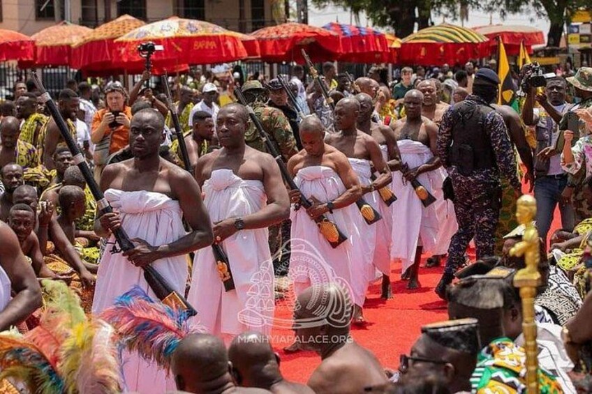 A group of people in traditional attire walking on a red carpet. 1