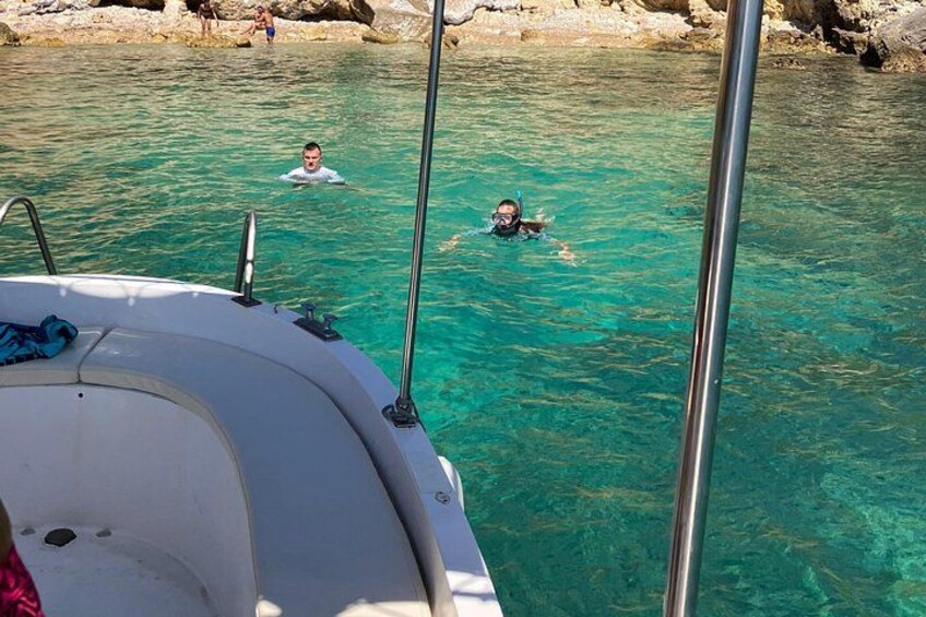 A boat with two people swimming in clear water. 5
