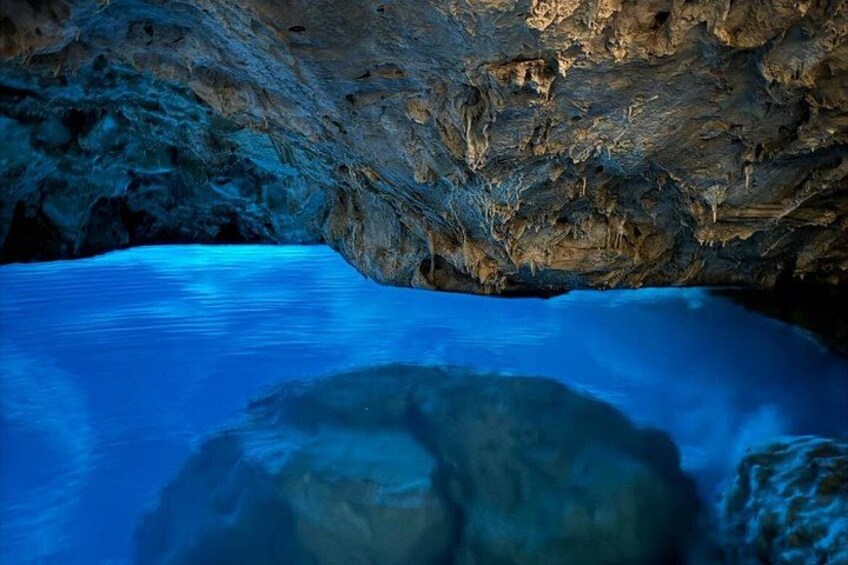 A cave interior with blue water and rock formations. 3