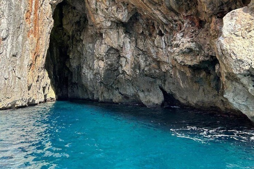 A natural rock formation with a clear blue pool at its base. 5