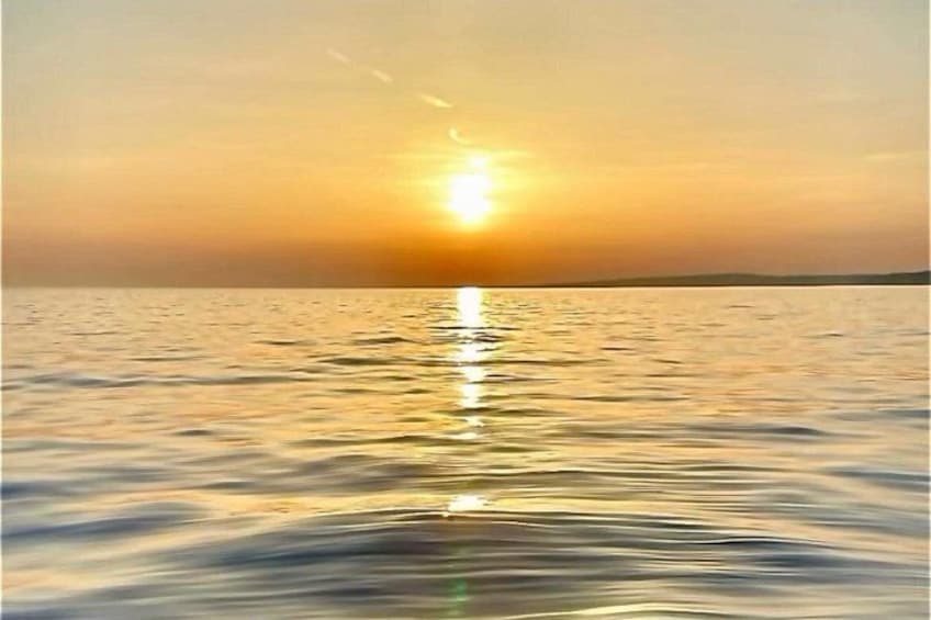 Een zonsondergang boven een rustige zee, met een duidelijke horizon. 3