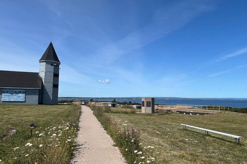 A coastal path leading to a lighthouse, a small tower, and a bench overlooking the sea. 2
