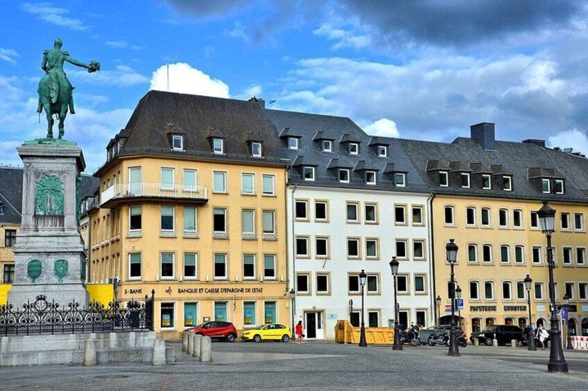 Une place de ville avec une statue, des bâtiments et une fontaine. 3