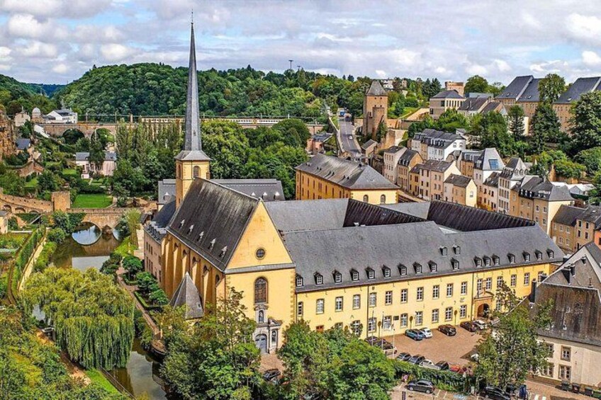 A historic town with a prominent church, a river, and surrounding greenery. 2