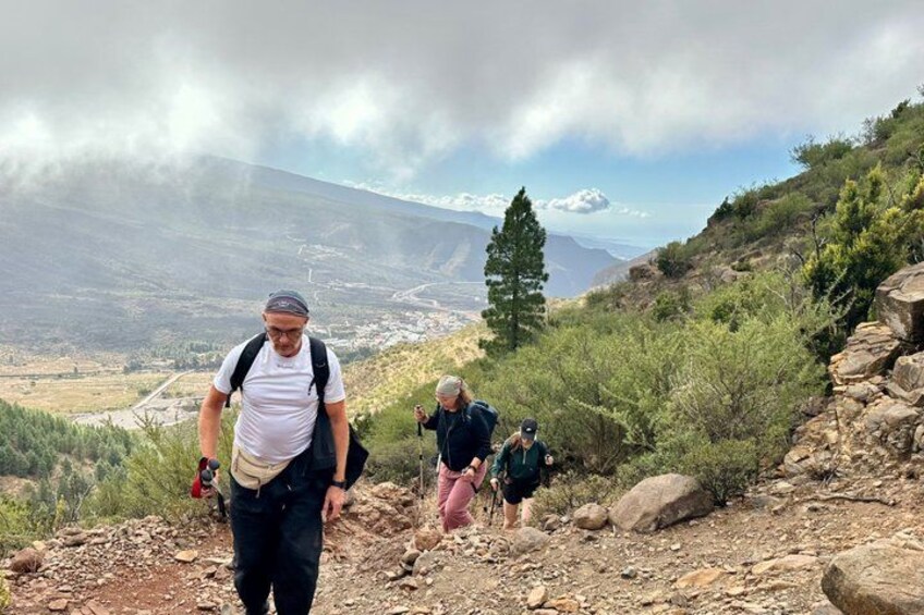 A hiker on a rocky trail with a mountainous landscape in the background. 3
