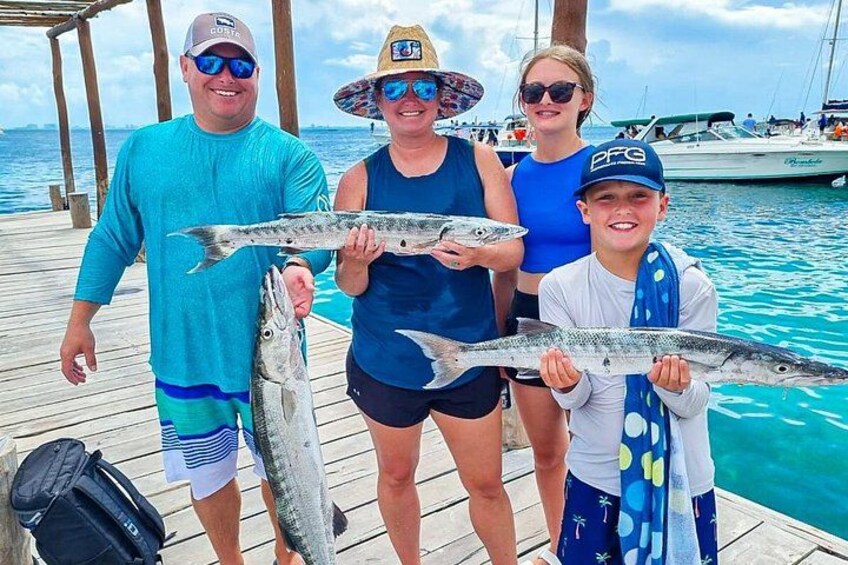 A group of people on a wooden dock holding fish. 3