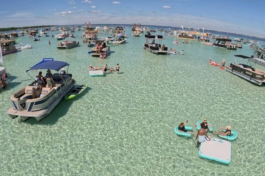 En fullsatt strand med många båtar och människor som ägnar sig åt olika vattenaktiviteter. 3