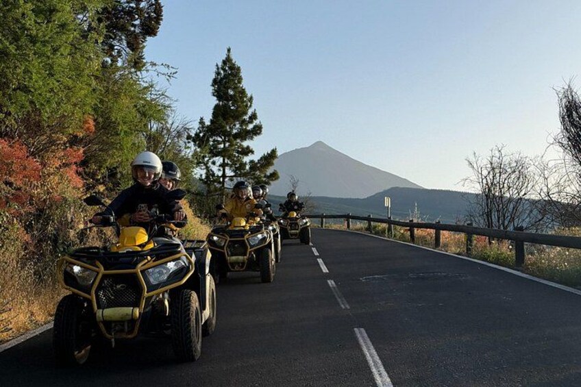 Un groupe de personnes conduisant des quads sur une route, avec une montagne en arrière-plan. 2