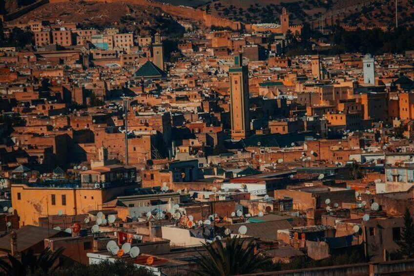 A densely packed urban landscape with numerous buildings, a prominent tower, and a hill in the background. 4