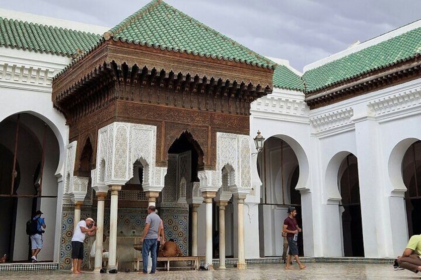 A courtyard with arches and a wooden structure with intricate carvings. 2