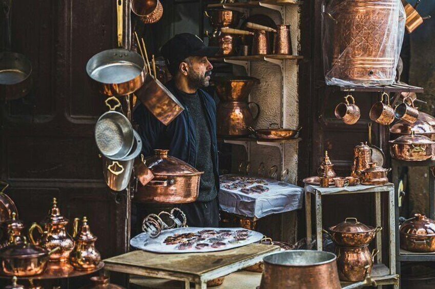 A person arranging copper cookware in a market stall. 5