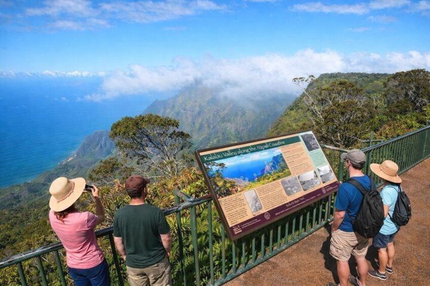 Un grupo de personas en un mirador con un gran cartel informativo sobre el Valle de Kalalau. 5