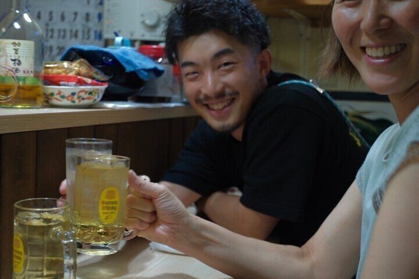 A person holding a bottle of beer and a glass of beer on a table. 3