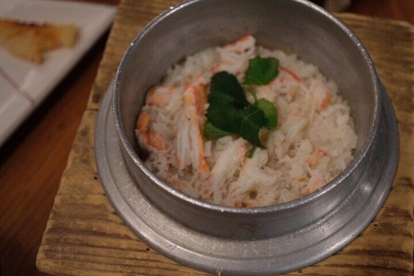 A metal bowl of rice with shrimp and a leaf garnish on a wooden table. 5