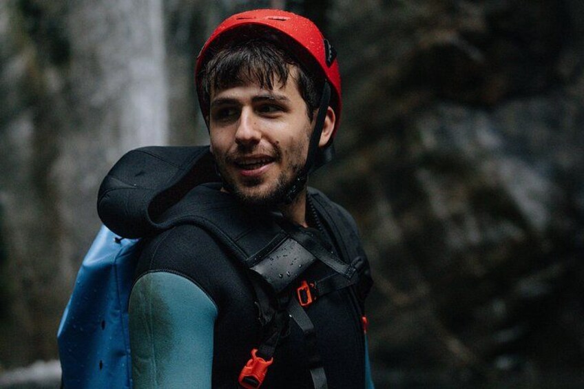 A person wearing a red helmet and a blue jacket with a backpack. 5