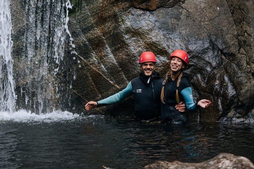 Two people in water with a waterfall in the background. 3