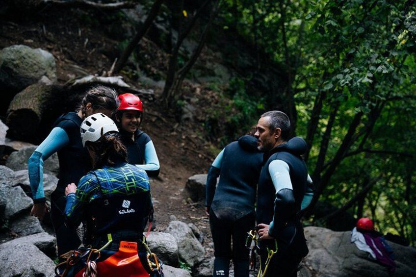 A group of people hiking in a forested area with large rocks and trees. 4
