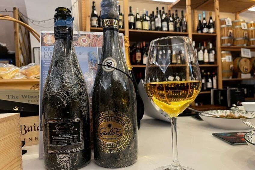 Två flaskor vin och ett vinglas står på en bänk. 2