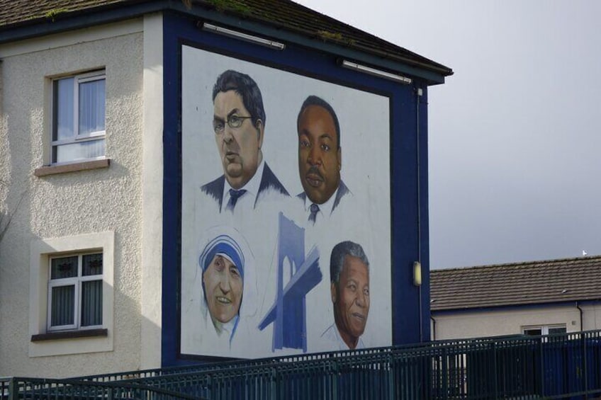A mural on a building featuring portraits of four individuals. 5