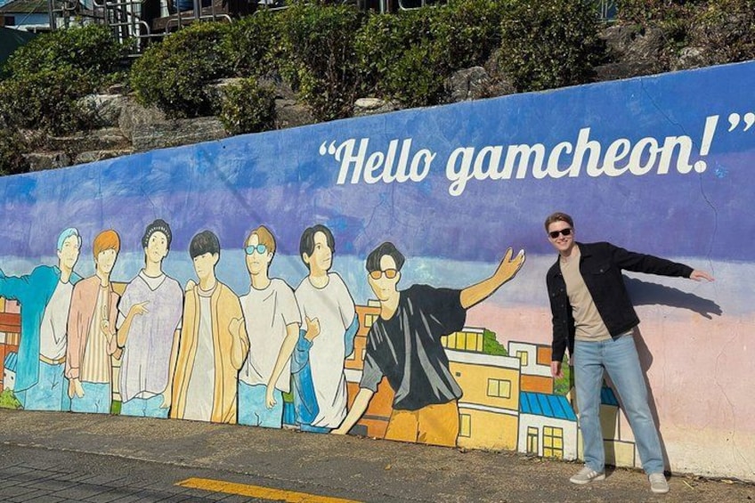Un mural con el texto 'Hello gamcheon!' y una persona de pie frente a él. 5
