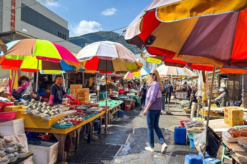 Un mercado al aire libre concurrido, con sombrillas de colores y varios puestos que venden productos. 4