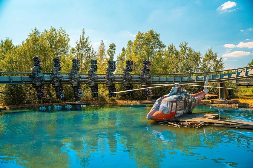 A helicopter parked near a body of water with a bridge in the background. 1
