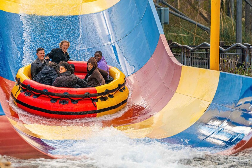 A group of people in a colorful inflatable raft sliding down a water slide. 5