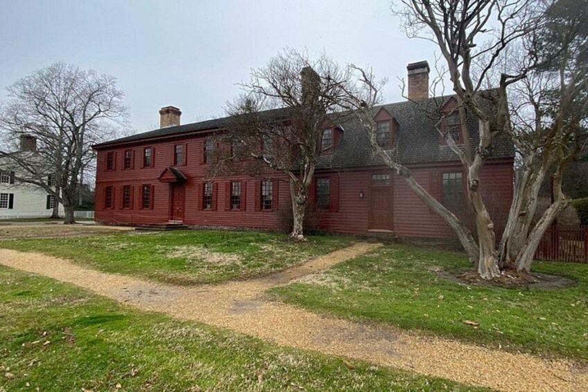 A red brick house with a chimney, surrounded by a grassy yard and a dirt path. 2