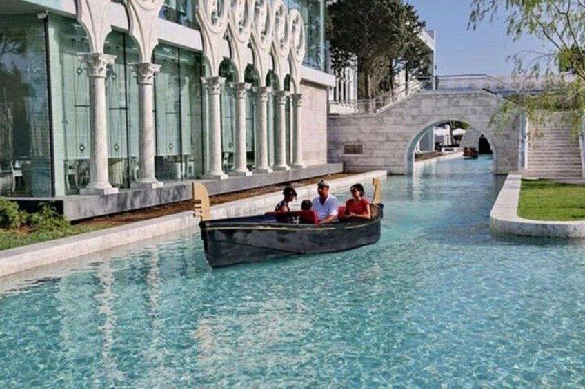 Ein Kanal mit einem Boot, das Menschen befördert, umgeben von klassischer Architektur und einer Brücke. 3