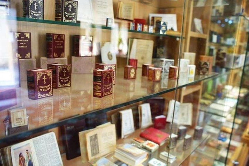 Een glazen vitrine met diverse religieuze boeken en voorwerpen. 5