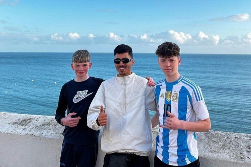Three people standing by a seaside with a clear sky and calm sea. 4